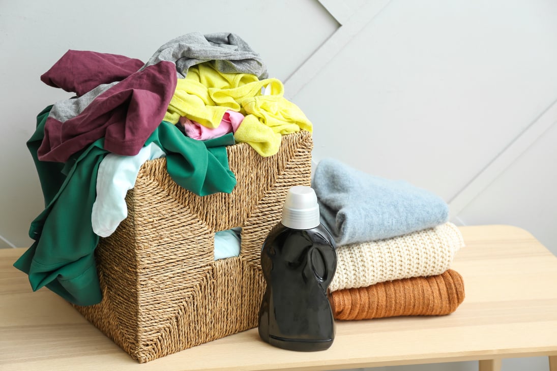 Basket with Dirty Clothes on Table near Light Wall