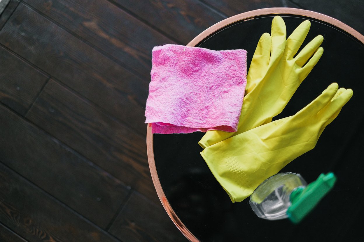 Latex gloves and bottle of cleaning product placed on table in room